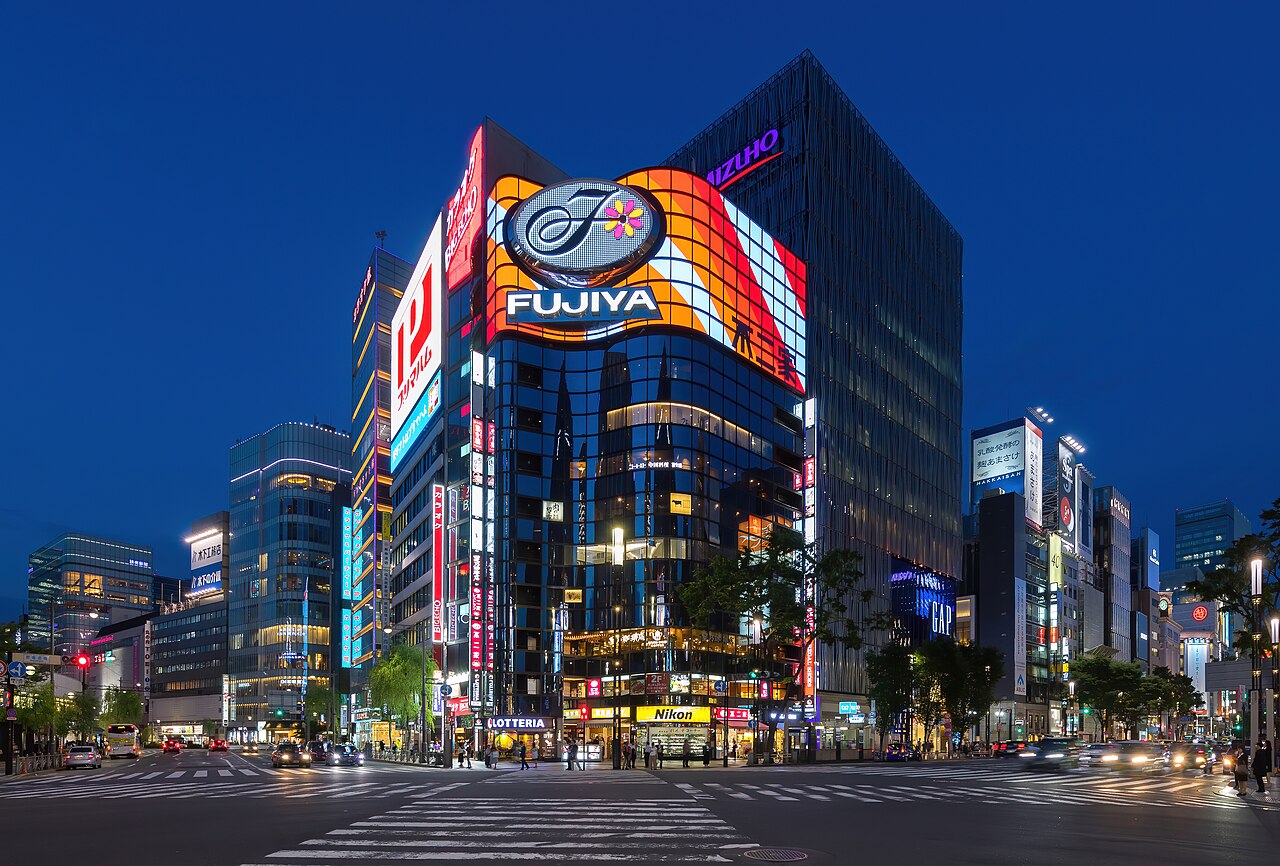 初めての東京観光5日間モデルコース!見どころとおすすめプラン 8 夜の銀座の交差点。ガラス張りビル上部の大型ネオンと、路面店の明かりが点灯している