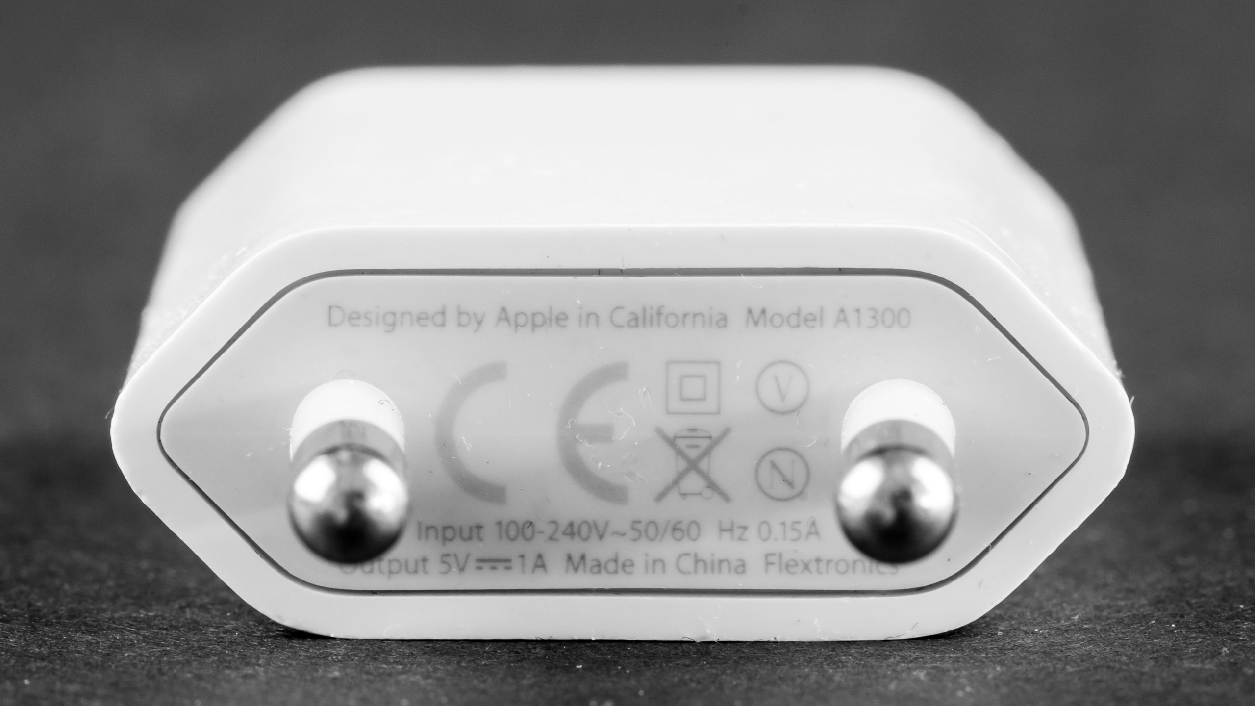 Apple の USB 電源アダプタ A1300 の側面。Input 100-240V〜50/60 Hz 0.15A、Output 5V 1A と刻印されている
