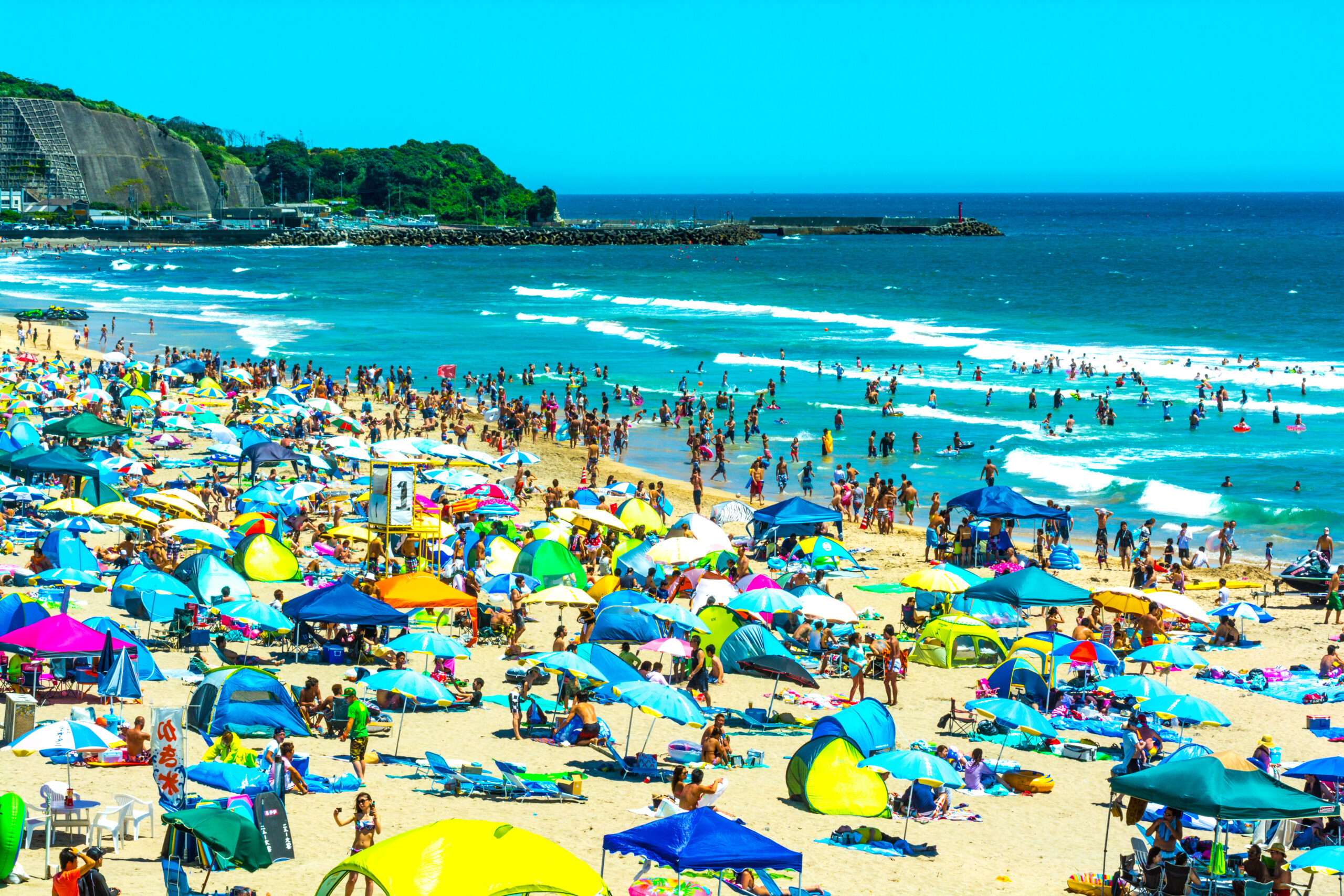 御宿 五氣里2026年7月開業!温泉・サウナ付ヴィラ 1 海水浴シーズンの御宿海岸。砂浜にパラソルとテントが並び、奥に防波堤が見える