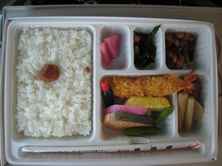 A makunouchi-style ekiben with rice, grilled salmon, fried prawn and pickles