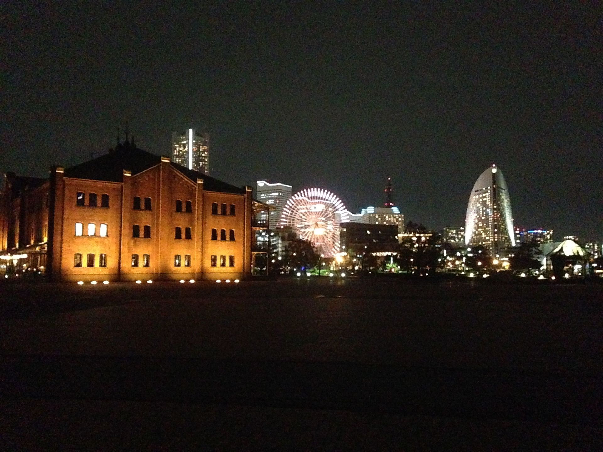 夜の横浜赤レンガ倉庫2号館と、背後に光る観覧車とみなとみらいの高層ビル群