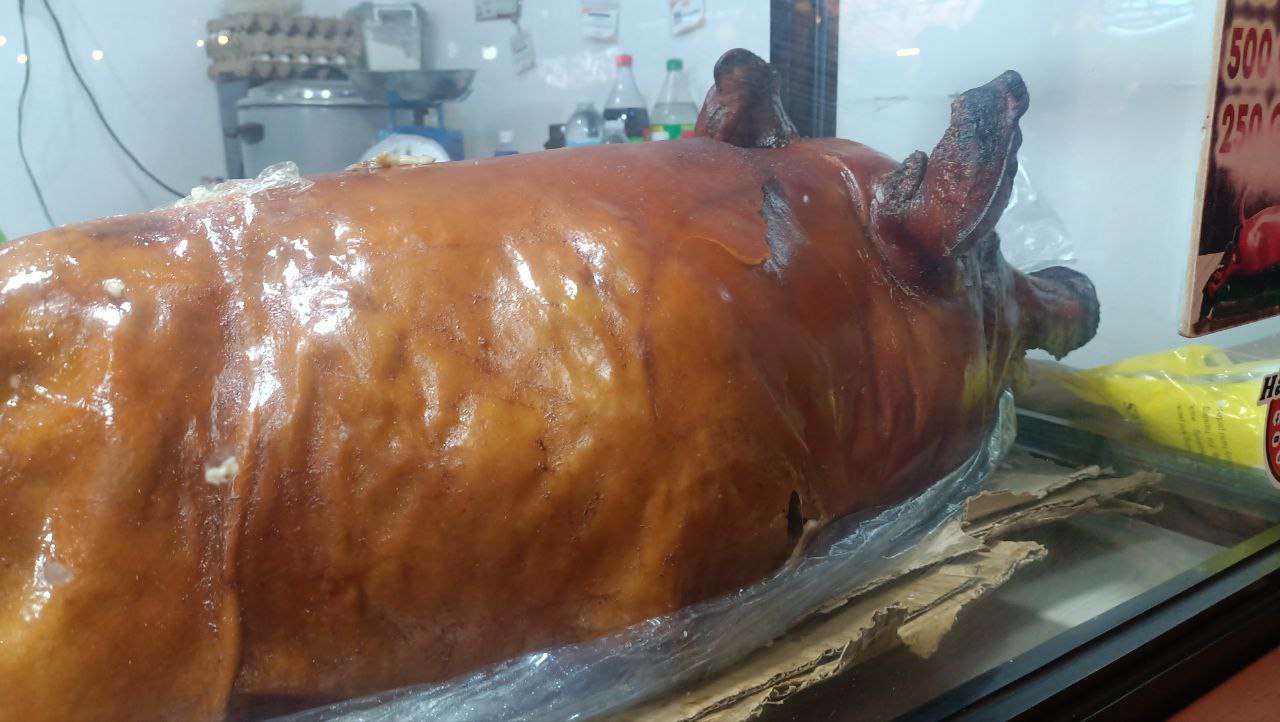屋台の陳列ケースに並ぶ、皮が飴色に焼けた豚の丸焼きレチョン