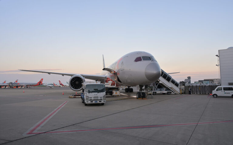 成田空港のエプロンに停まり、タラップと作業車が付いたジェットスター航空のボーイング787-8型機