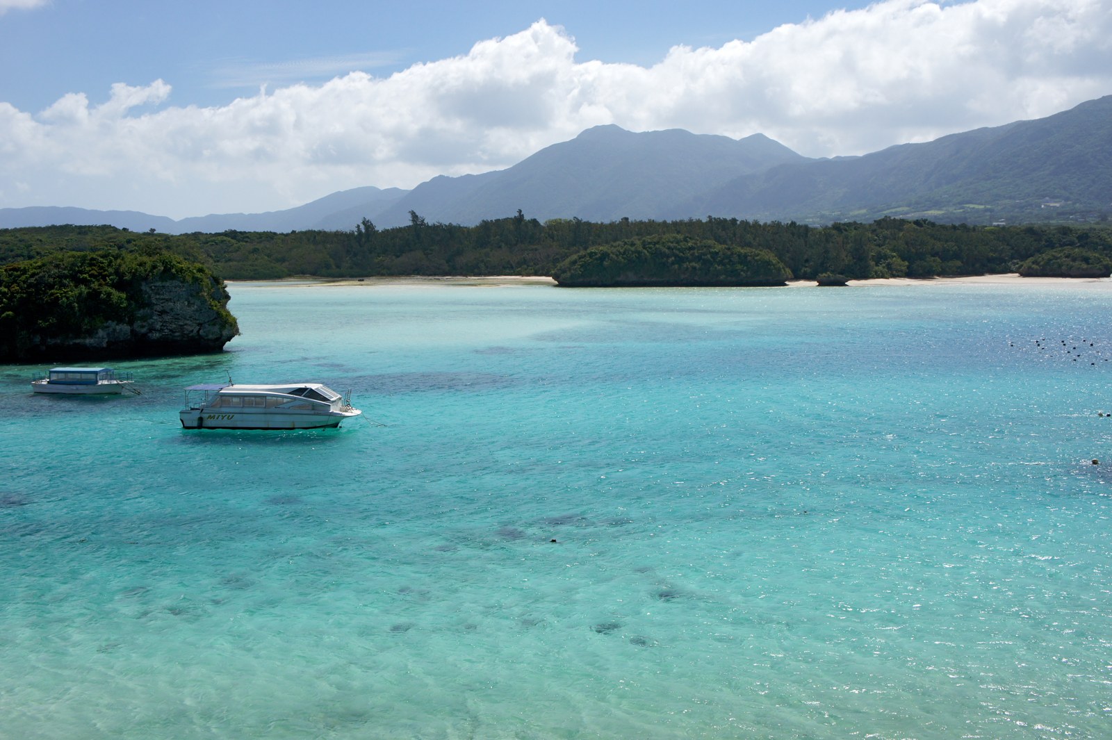 川平湾の浅瀬に浮かぶグラスボートと背後の於茂登岳